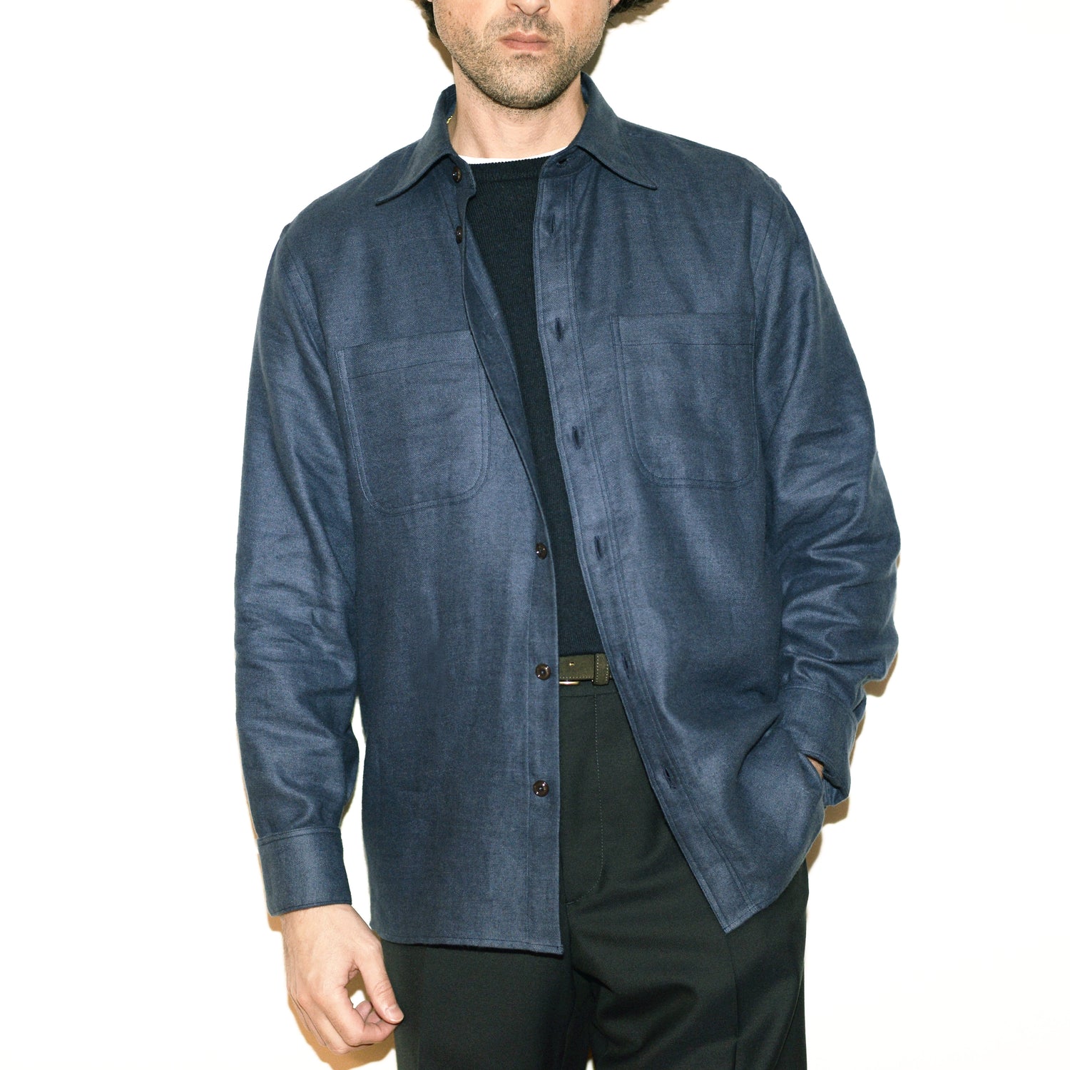 Model wears Brooklyn Tailors BKT16 Overshirt in Linen Flannel - Slate Blue open over black sweater with black pants and olive belt